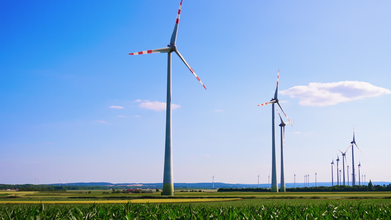 Powerful wind turbines rotate in the wind. Low angle view at the wind mills in the fields