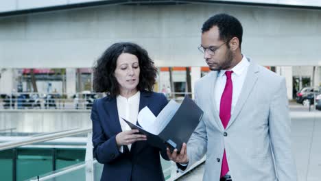 coworkers discussing documents on street