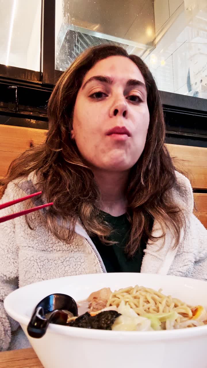 Woman enjoying delicious ramen noodles at restaurant