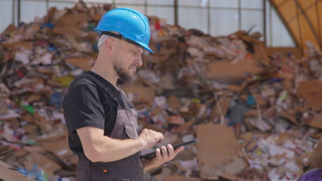 trabajador en una planta de reciclaje al aire libre usa una tableta, mitad del cuerpo disparado