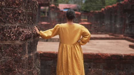 Woman-in-a-yellow-dress-explores-ancient-ruins-on-a-sunny-day