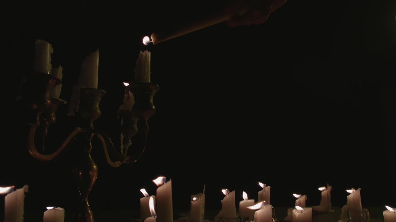 un grupo de velas encendidas de velas blancas, algunas en un candelabro que se encienden y funcionan durante un tiempo en cámara lenta