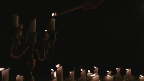 a candle lighting group of white candles some on a candelabra getting lit up and running for a while in slow motion