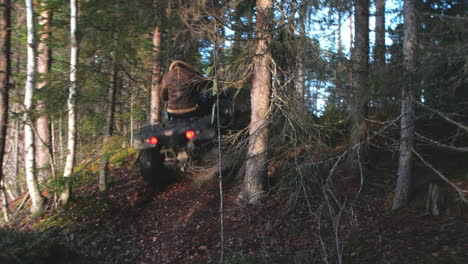 man driving a atv through the forrest