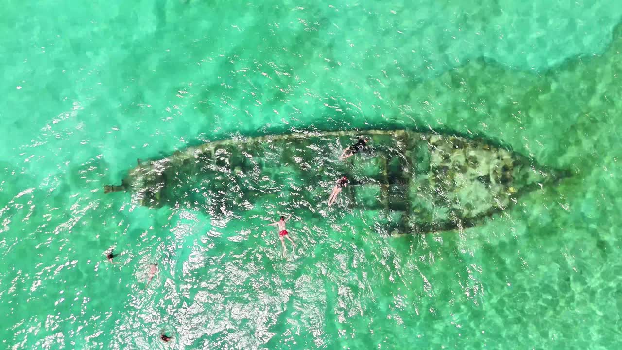 Drone shot over a sunken ship surrounded by snorkelers in the crystal-clear shallows near Darocotan Island, Palawan—an iconic marine attraction in the Philippine archipelago