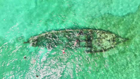 drone shot over a sunken ship surrounded by snorkelers in the crystal-clear shallows near darocotan island, palawan—an iconic marine attraction in the philippine archipelago