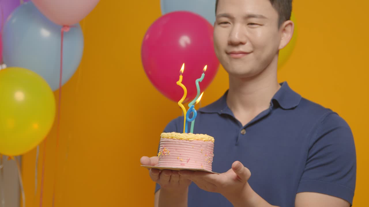 불로 케이크를 들고 생일을 축하하는 파티 모자를 입은 남자의 스튜디오 초상화