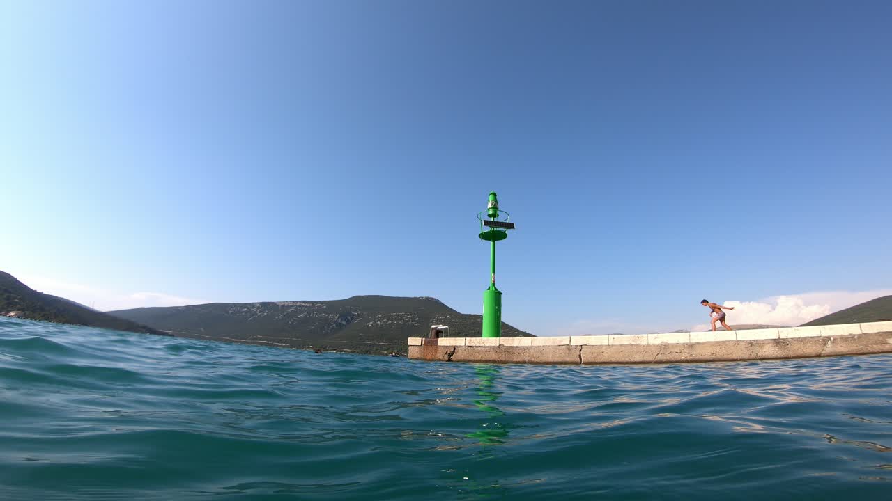 A kid is preparing to jump and giving up and leaving. The view from the sea level.