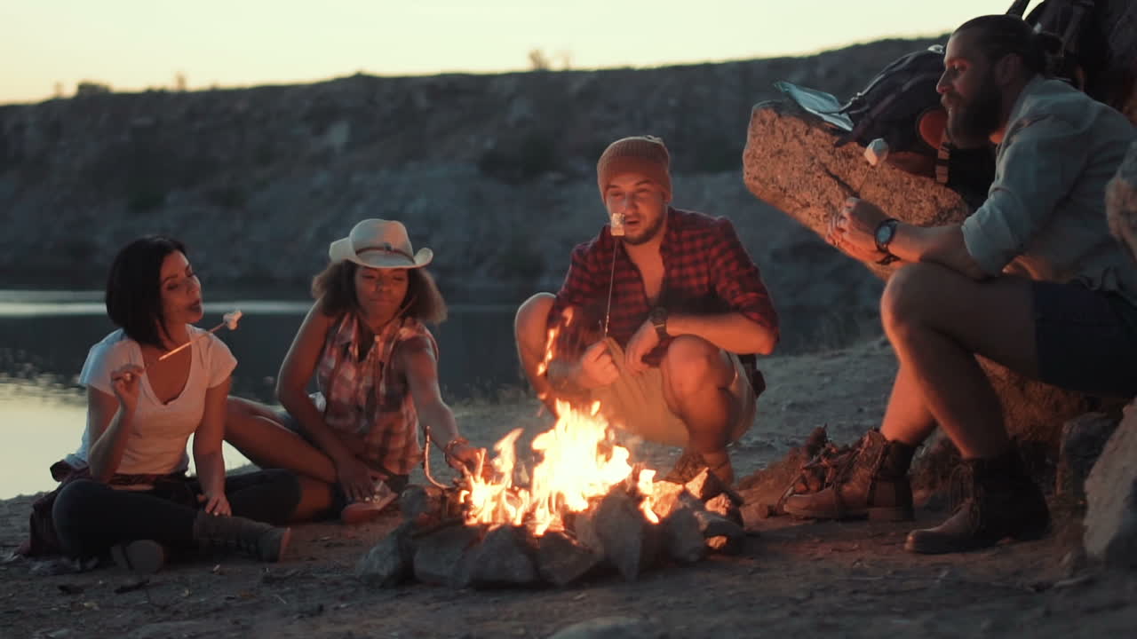 Friends camping around a campfire roasting marshmallows
