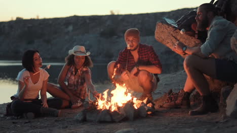 friends camping around a campfire roasting marshmallows