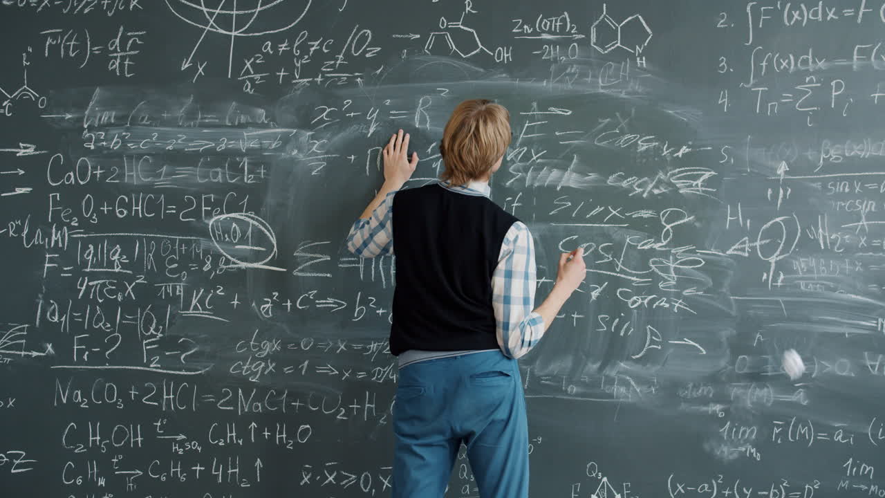 Man writing on a chalkboard full of equations