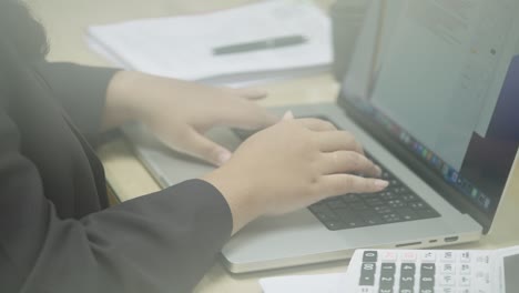 las manos de la mujer de negocios escribiendo en el teclado de la computadora portátil para buscar información, informe de investigación de marketing en el escritorio de la oficina