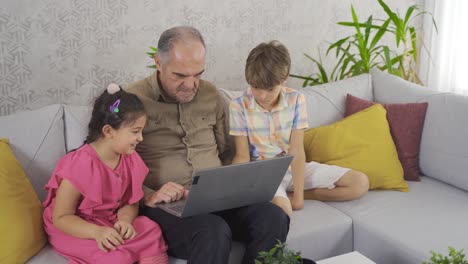 Grandfather-and-grandchildren-looking-at-laptop.