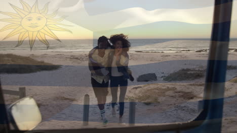 animación de la bandera de uruguay sobre una pareja afroamericana en la playa