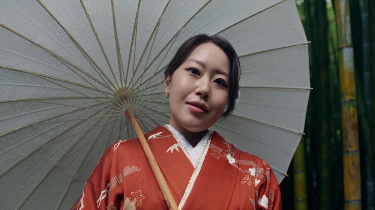 Donna in Kimono con ombrello in una foresta di bambù