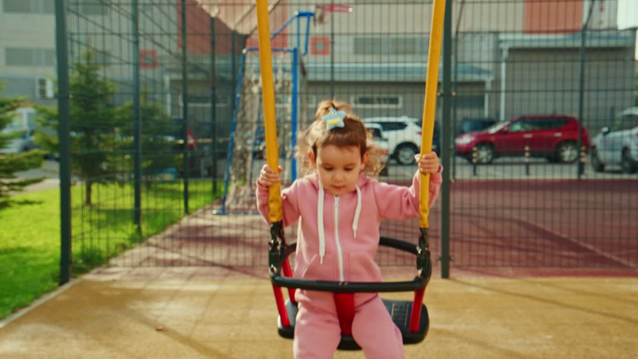 Una bambina felice si dondola in aria, vivendo l'euforia del gioco in un vivace parco giochi, mostrando la felicità infantile e i momenti spensierati