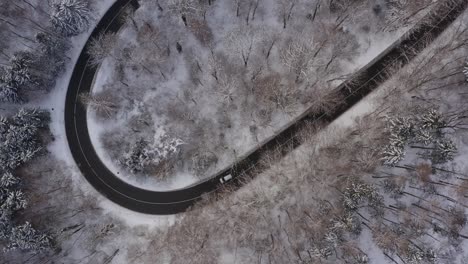 Snowy-look-up-aerial-shot-from-the-winding-street-with-a-driving-car,-up-to-the-tourism-hotspot-monstery-Schaeftlarn-placed-in-a-beautiful-winter-landscape-with-the-alp-mountains-in-the-background