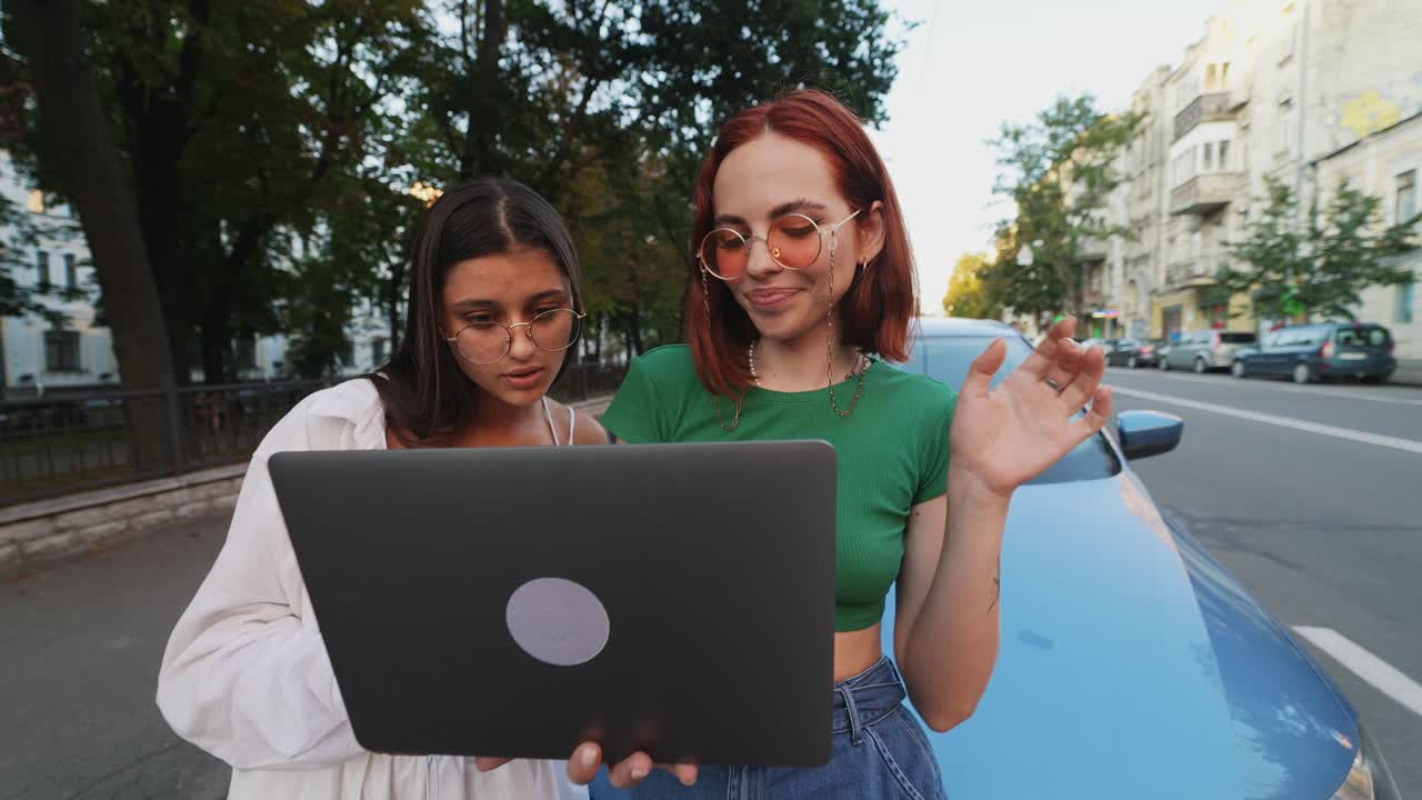 dos amigos mirando una computadora portátil en la calle