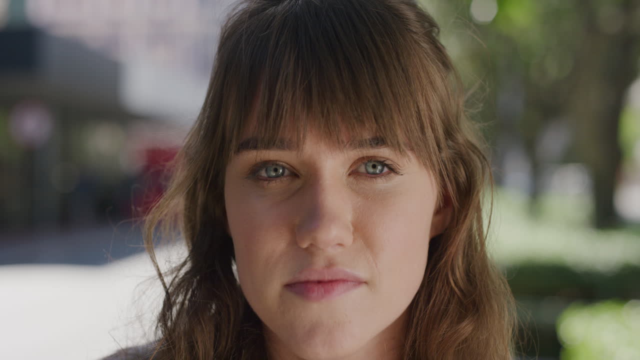 retrato en primer plano de una hermosa mujer joven mirando a la cámara mujer caucásica tranquila mirando contemplativa en el fondo de la ciudad urbana en cámara lenta