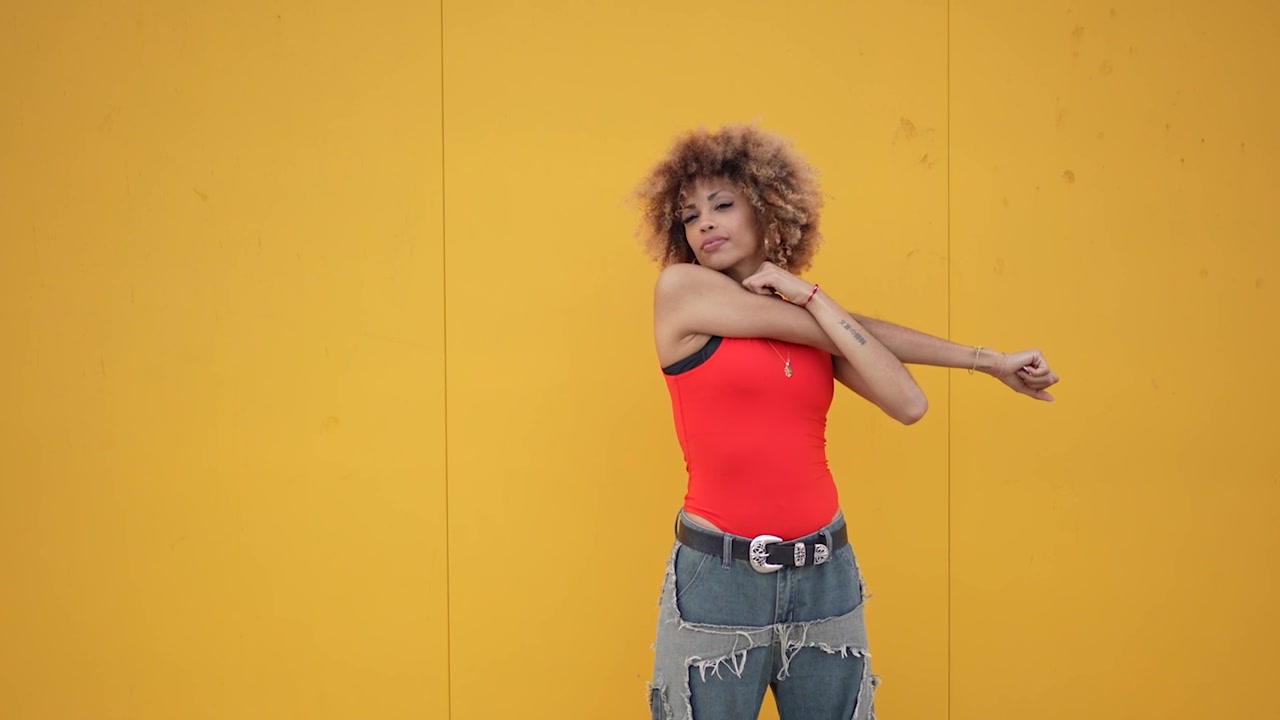 A contemporary dance pose set against a striking and vibrant yellow wall background