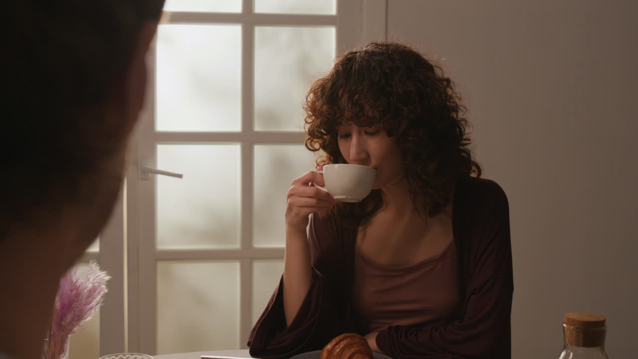 Woman with curly hair enjoying coffee at breakfast