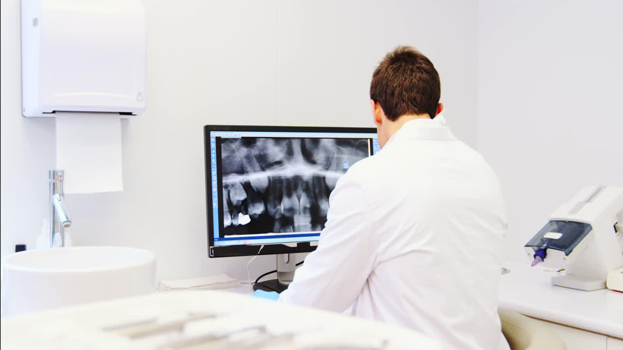 Attentive dentist examining x-ray report on computer