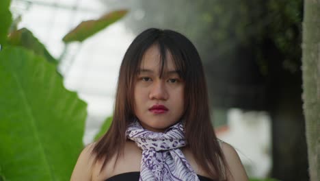 indonesian woman wearing a scarf, with a blurry nature backdrop