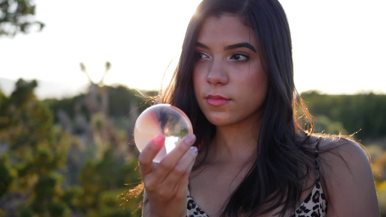 una hermosa mujer hispana de ensueño en un mundo de fantasía mística con una bola de cristal mágica y una mirada sensual a cámara lenta