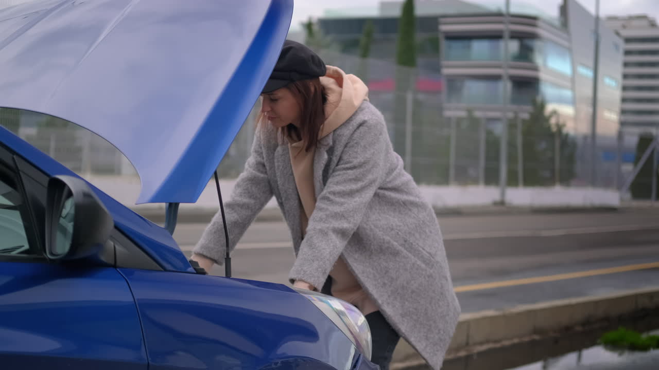 mujer arreglando un coche azul averiado