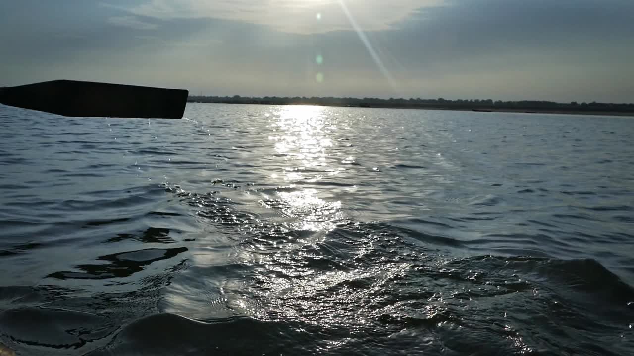 Person Paddling During Sunrise On The Water Of River Ganges In Varanasi City, State Of Uttar Pradesh, India. - Close Up Shot