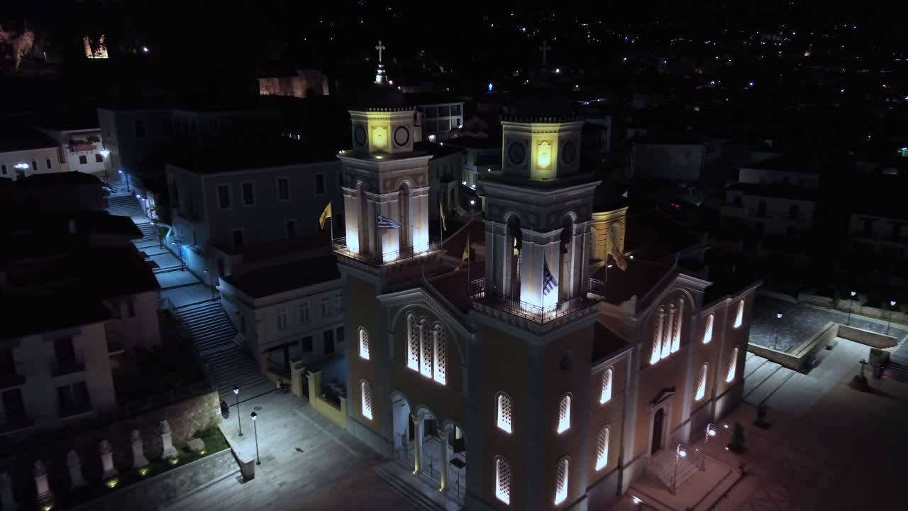 Aerial high angle, bird's eye view, push in drop down establishing shot, iconic greek christian orthodox Ypapanti church, located at historical center of Kalamata, night 4K