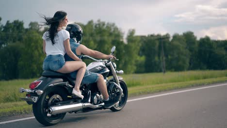 una joven pareja en denim vestido de verano viaja a lo largo de la carretera gris