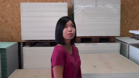 mujer japonesa mirando alrededor en una ferretería con materiales en el fondo