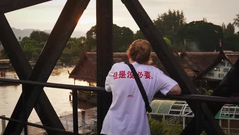 female european tourist visiting the death railway overlooking the khwae yai river in kanchanburi, thailand