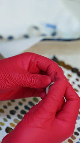 artificial eye in doctor's hands. medical specialist in latex gloves holding eye prosthesis on paints background. vertical video