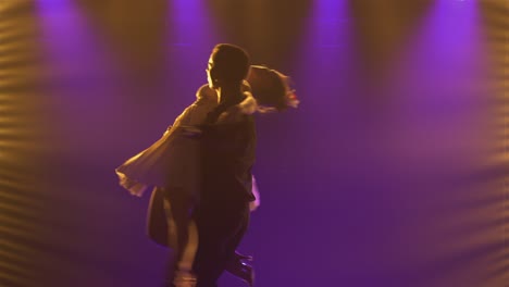 silhouettes of dancers performing on stage with dramatic lighting