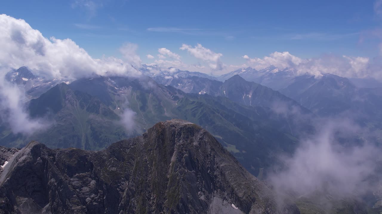 cima de una montaña en los alpes austriacos rodeada de nubes sombrías y un cielo azul de pájaros