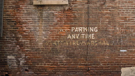 brick wall with painted no parking anytime - fire marshal sign