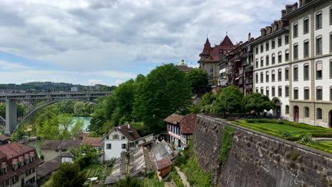 aerial panning shot of ancient houses with river view and famous bridge of bern in background. historic buildings in city capital of switzerland. sunny day with clouds in summer. panorama wide shot.