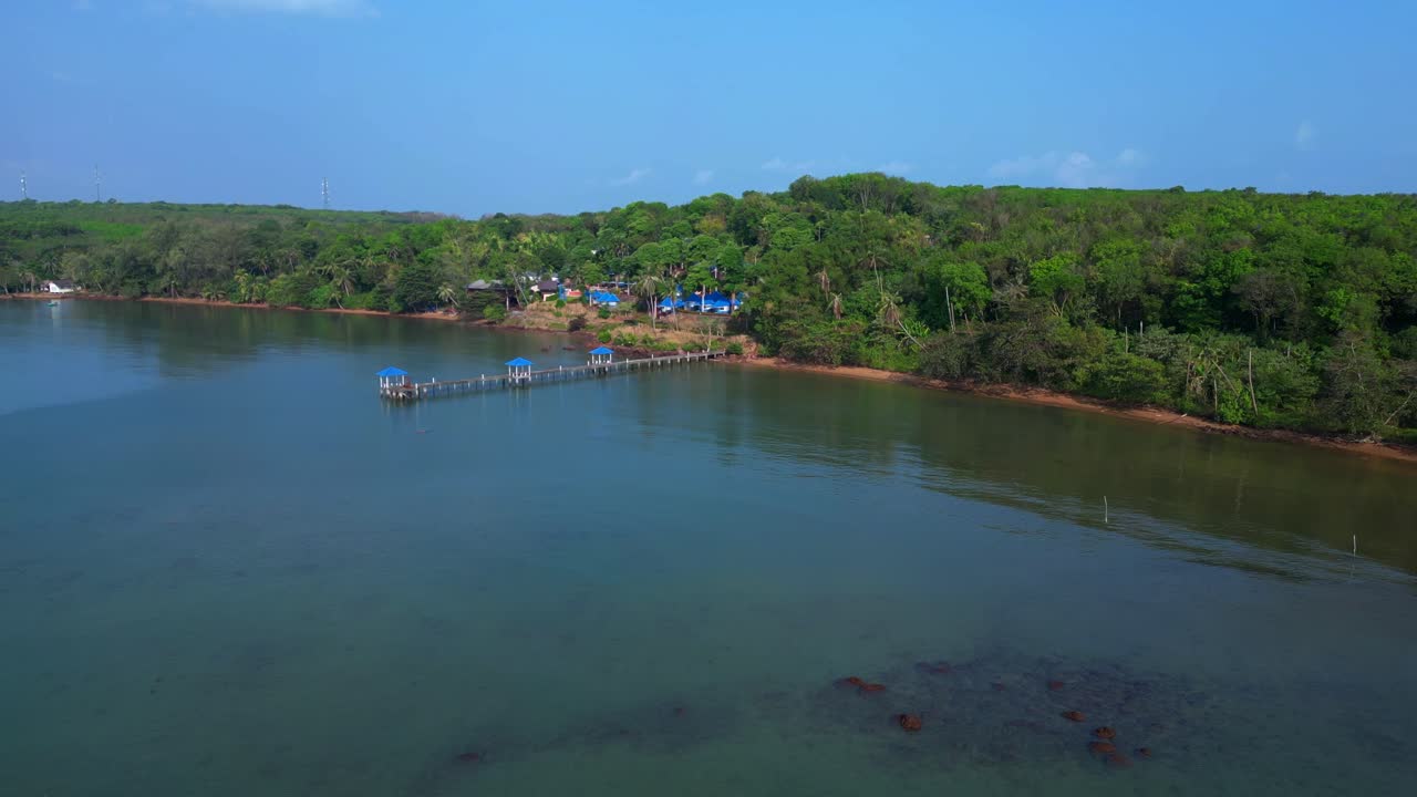 Koh Mak tropical island in Thailand showing luxury glamping tents on the coast near the pier surrounded by lush vegetation. Fabulous aerial view flight fly push forward drone