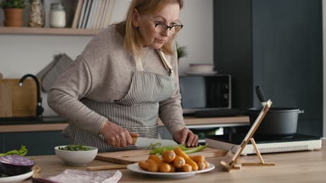 Kaukasische-Seniorin-Schält-Eine-Karotte,-Während-Sie-In-Der-Küche-Kocht