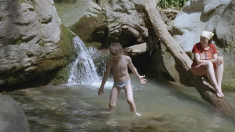 mother and son playing in a mountain stream