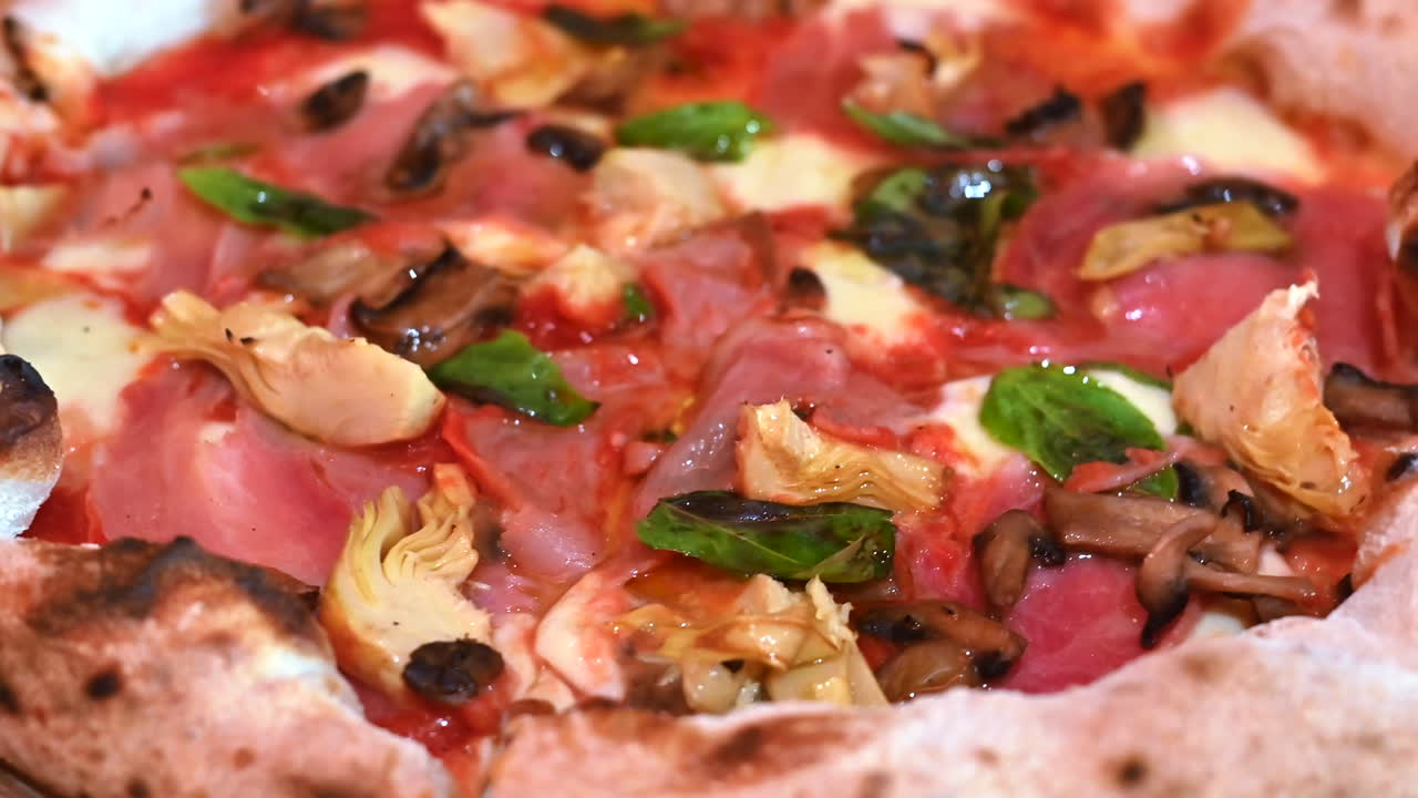 Pizza with mushroom prosciuto and artichoke, close up