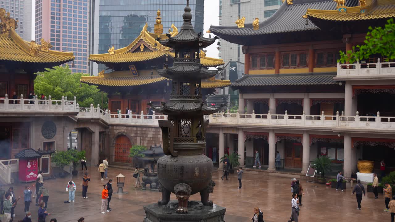 Jingan Temple golden roofs amid Shanghai's modern skyline outside its yard, China
