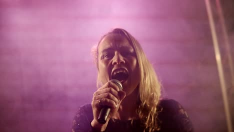 backlit silhouette of singer vocalist girl with short hair standing in nightclub disco studio and start singing performance with mic in hand