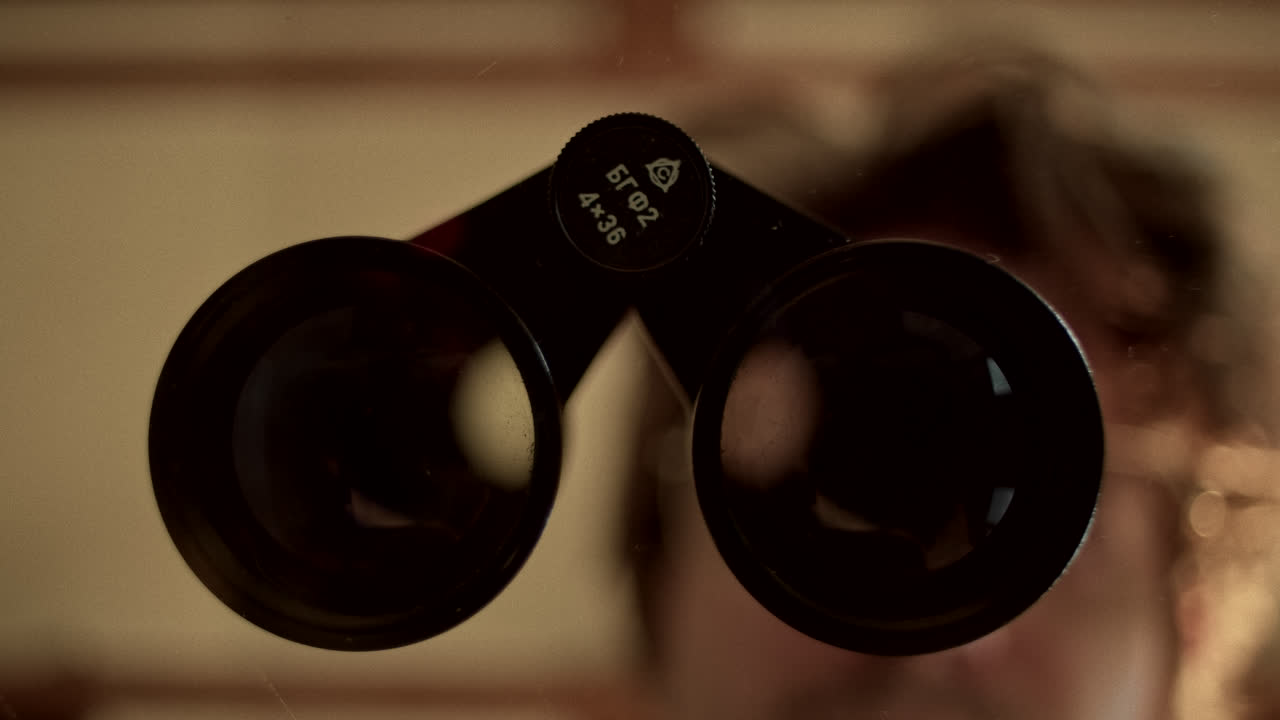 A pair of binoculars with a blurred reflection of a person