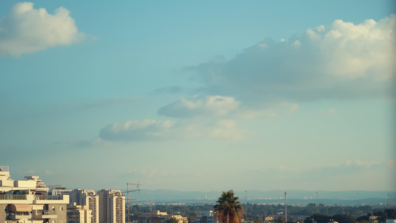 Cena em time-lapse de nuvens deslizando no céu azul, árvore verde, paisagem urbana e uma palmeira ao fundo, Vídeo 4K.