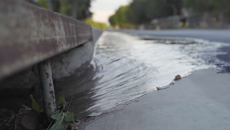 Agua-Que-Fluye-Rápidamente-Hacia-El-Desagüe-De-Alcantarillado-De-La-Ciudad-Con-Escombros