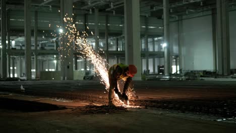 trabajador industrial está cortando barras de refuerzo metálicas con una sierra circular. construcción de una fábrica, hangar