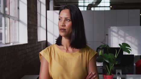 Portrait-of-mixed-race-businesswoman-looking-ahead-then-shifting-gaze-to-camera-and-smiling